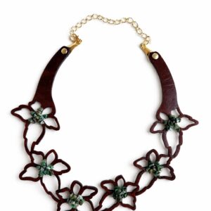Gargantilla de cuero marrón con flores caladas y centros de piedras semipreciosas sobre fondo blanco.